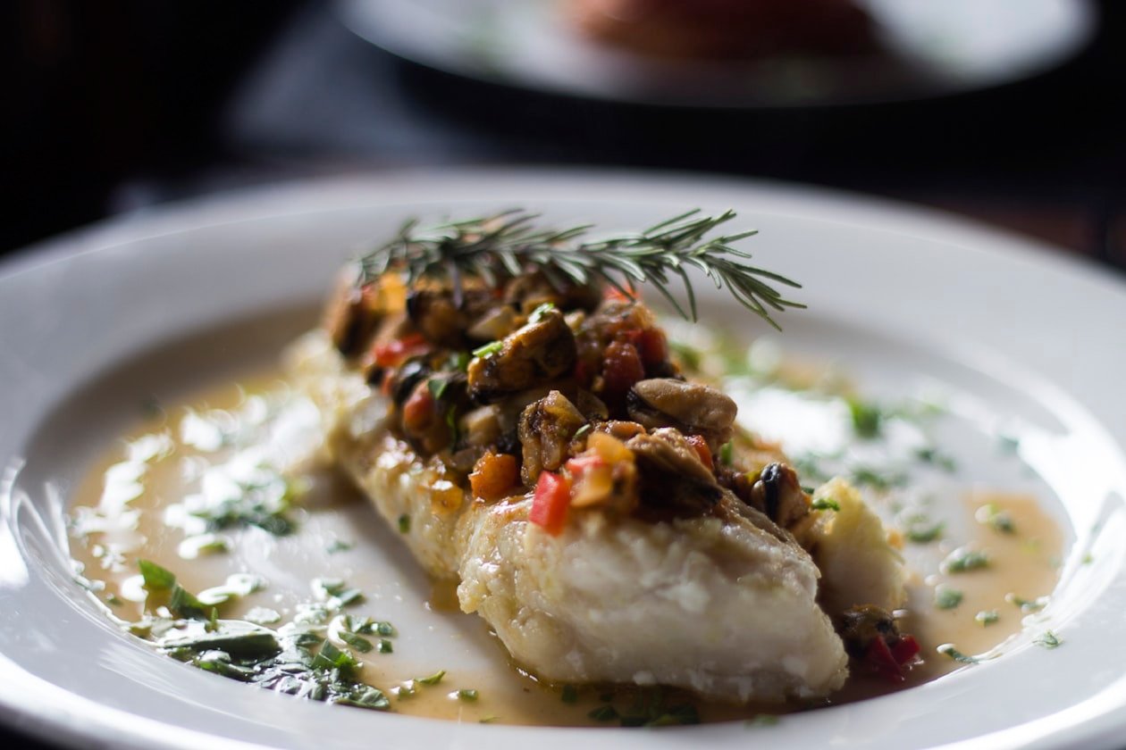 Filetto di baccalà cotto nel piatto con rosmarino e frutti di mare