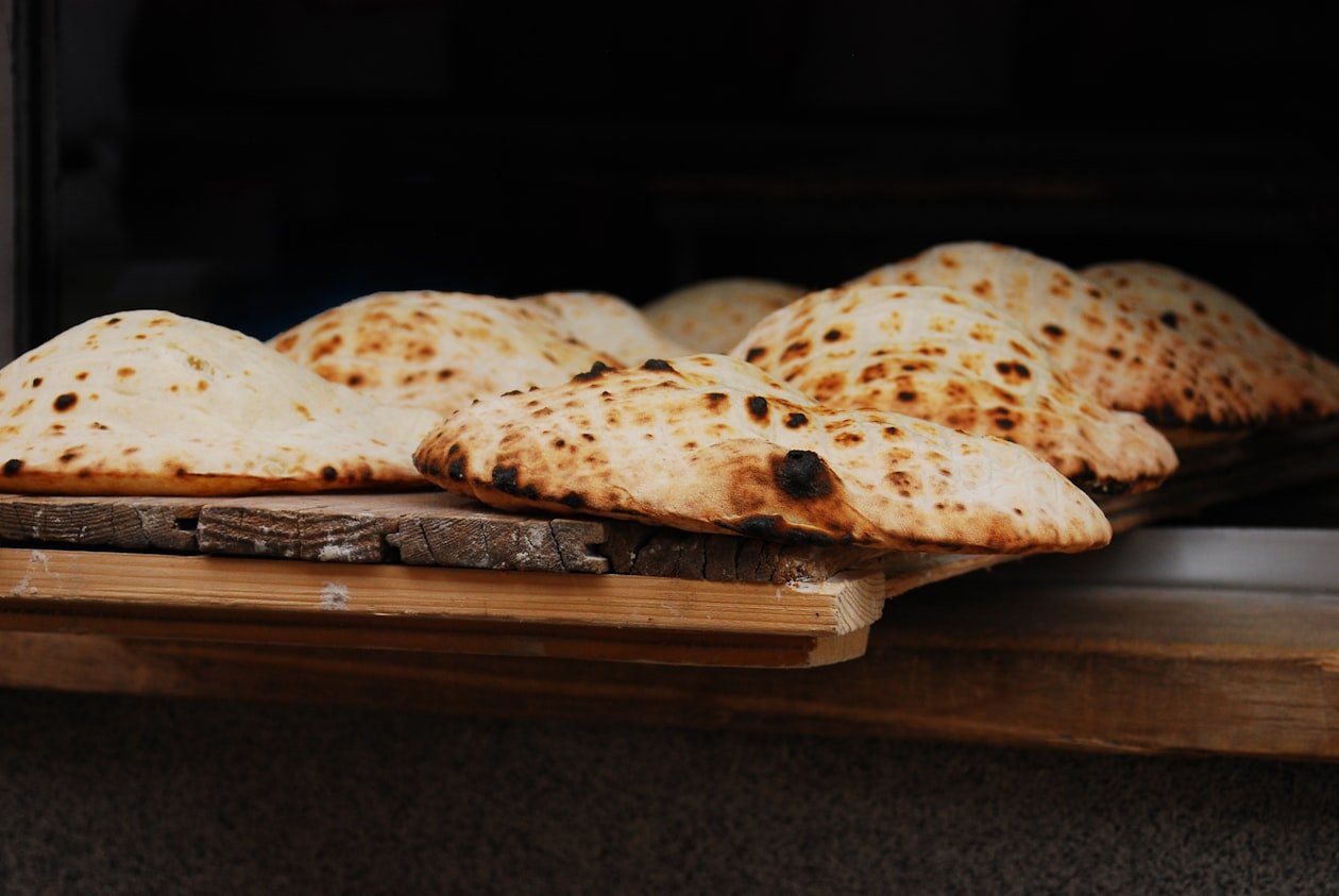 Pani piatti appena sfornati su assi di legno davanti al forno