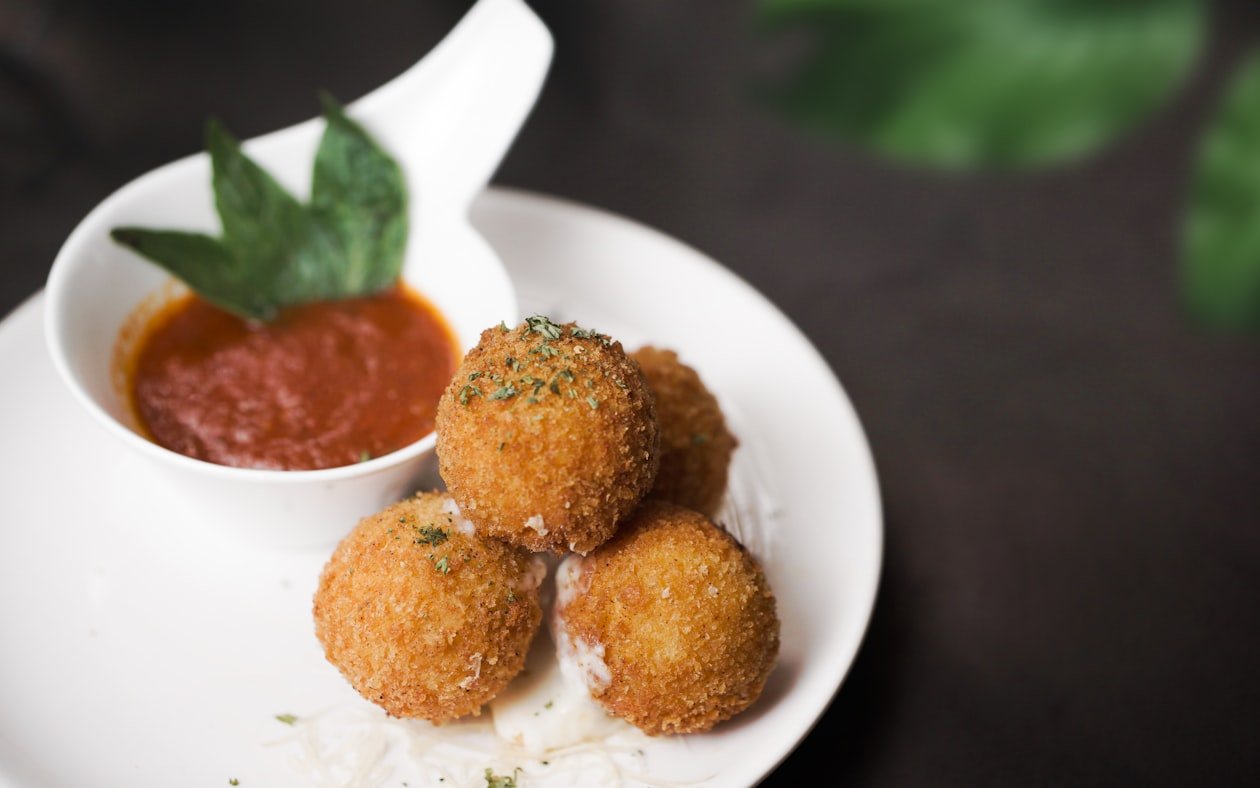 Arancini dorati serviti su piatto bianco