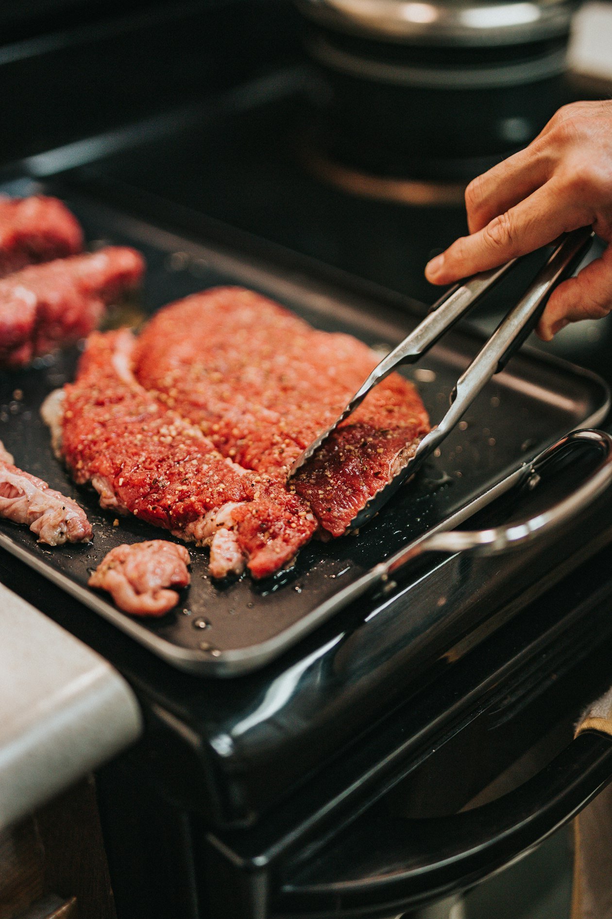 Mani che impanano una fetta di carne nel pangrattato