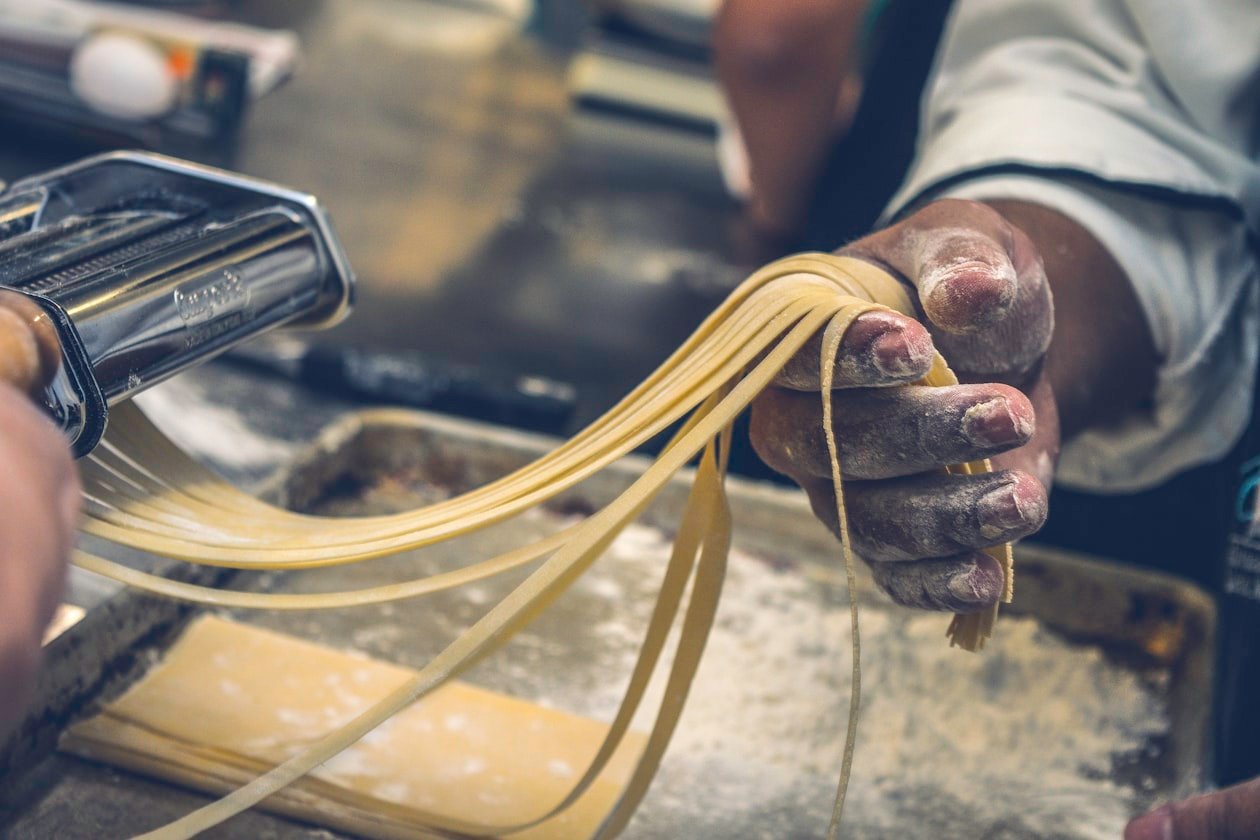 Mani che servono una porzione di lasagna fumante