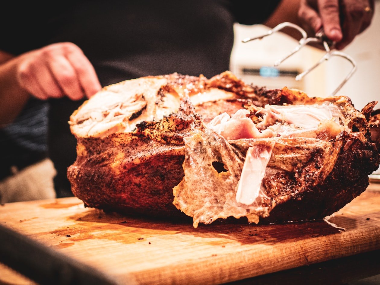 Mani che tagliano la porchetta appena sfornata