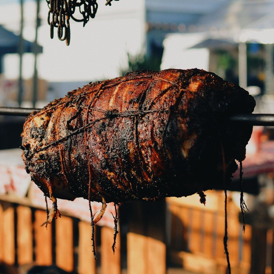Porchetta allo spiedo appesa al banco di una sagra