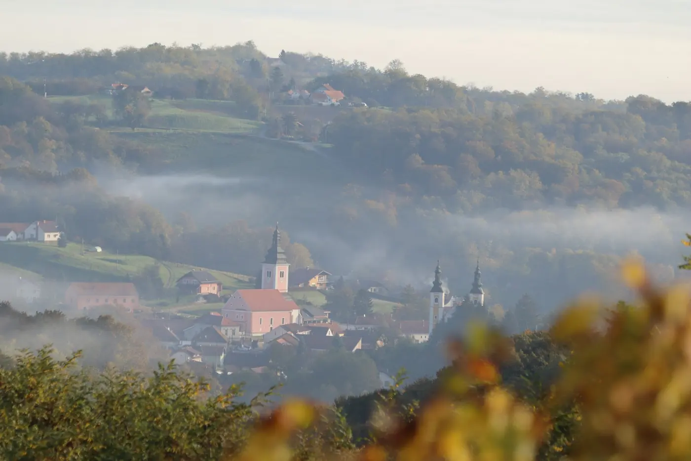 Colline coltivate a vigneto al tramonto, con un borgo sul crinale