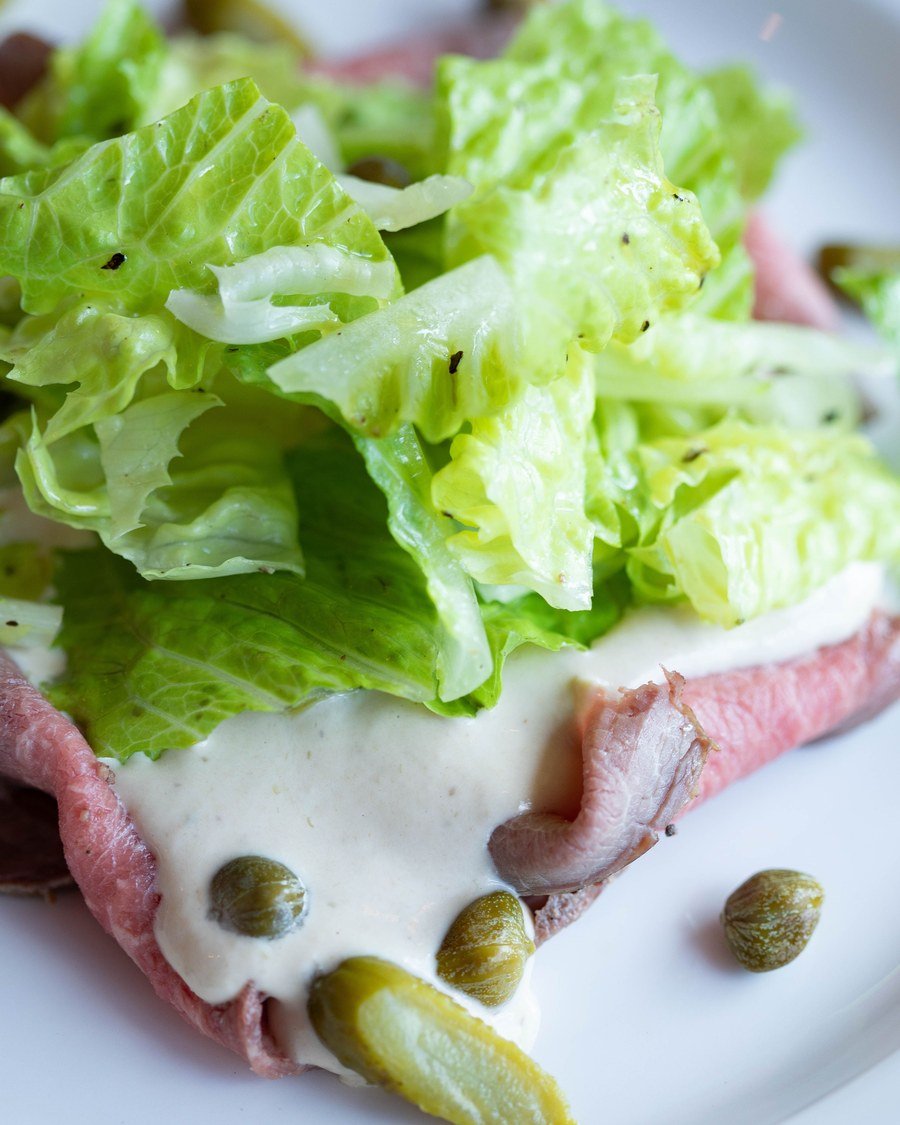 Fetta di vitello tonnato con insalata e capperi in primo piano